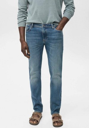 Blauwe spijkerbroeken met een rechte snit,Featuring een vervaagde wassing en vijf zakken. Gedragen met bruine sandalen en een lichtgrijze blouse met lange mouwen.