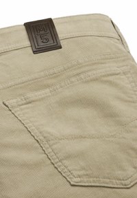Beige corduroy pants back pocket with detailed stitching and a brown leather brand label marked "M 5" above the pocket.