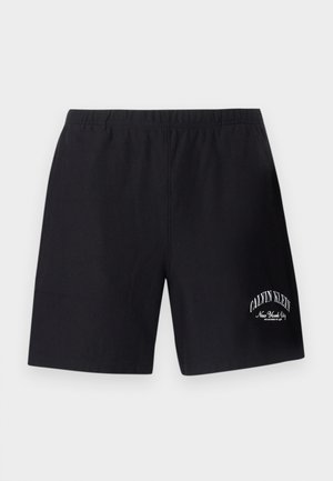 Czarne szorty z elastycznym pasem, z białym logo „Calvin Klein New York City” na dolnej części prawej nogawki.