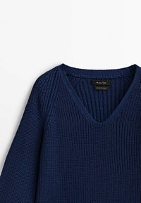 Marineblauer Strickpullover mit V-Ausschnitt, ausgestattet mit einer gerippten Struktur und langen Ärmeln. Das Etikett weist auf "Hergestellt in der Türkei" hin.
