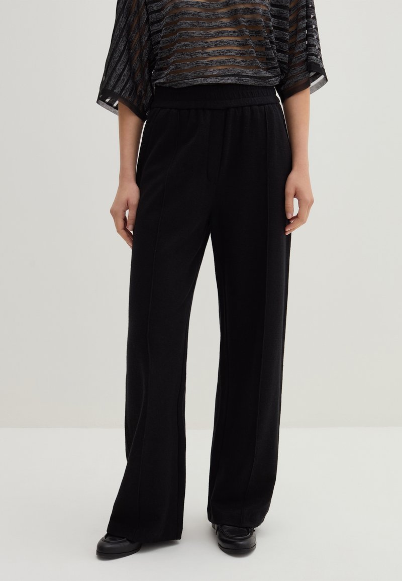 Schwarze weite Hosen aus einem weichen Stoff mit glatter Textur. Verfügt über einen hohen Bund und Vorderfalten für zusätzliche Details.
