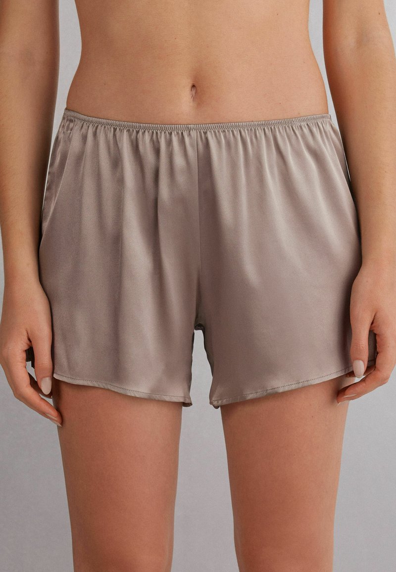 Shorts en satin de couleur taupe clair avec une taille élastique, dotés d'une coupe ample et de poches latérales pour plus de commodité.