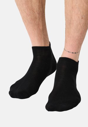 Sorte ankelsokker lavet af tynd, strækbar stof. Designet har en glat struktur med ribbet kant og uden synlige logoer eller mønstre.