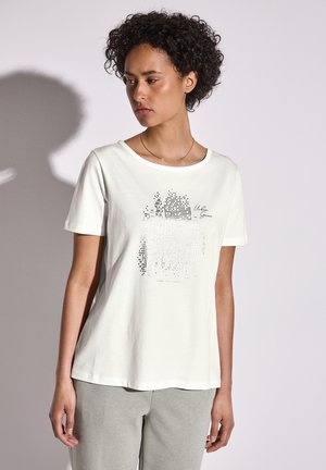 Camiseta blanca de manga corta hecha de algodón, con un diseño gráfico pixelado en negro, escote redondeado y corte relajado.