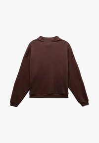 Sudadera marrón de gran tamaño con un cuello alto, puños y dobladillo acanalados. Hecha de una tela suave y texturizada, presenta un corte relajado y sin patrones distintivos.