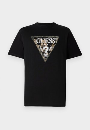 Black cotton t-shirt featuring a triangular printed logo in gold and white with floral accents and the text “GUESS” at the center.