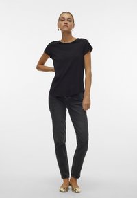 Black short-sleeve top with a rounded neckline, paired with dark gray jeans and gold flats. Simple design, lightweight fabric, smooth texture.