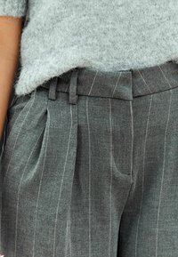 Graue Wollmischungshosen mit strukturiertem Finish, featuring feinen Nadelstreifen, Falten und einem strukturierten Taillenbund mit Gürtelschlaufen.