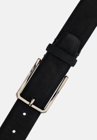 Melnas zamšādas jostas ar metālisku sudraba taisnstūra sprādzi. Aprīkota ar regulējamiem caurumiem izmēra pielāgošanai un vienkāršu, minimālistisku dizainu.