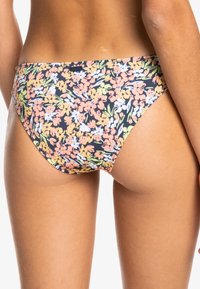 Blommig bikiniunderdel med svart bakgrund och färgglada blommönster i rosa, gult och vitt. Mjuk, töjbar tyg med medelhög täckning.