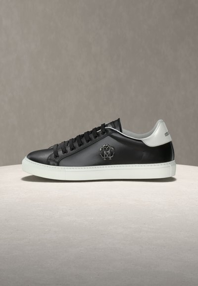 Baskets basses en cuir noir avec semelle blanche et languette de talon, lacets noirs et logo en relief sur le panneau latéral.