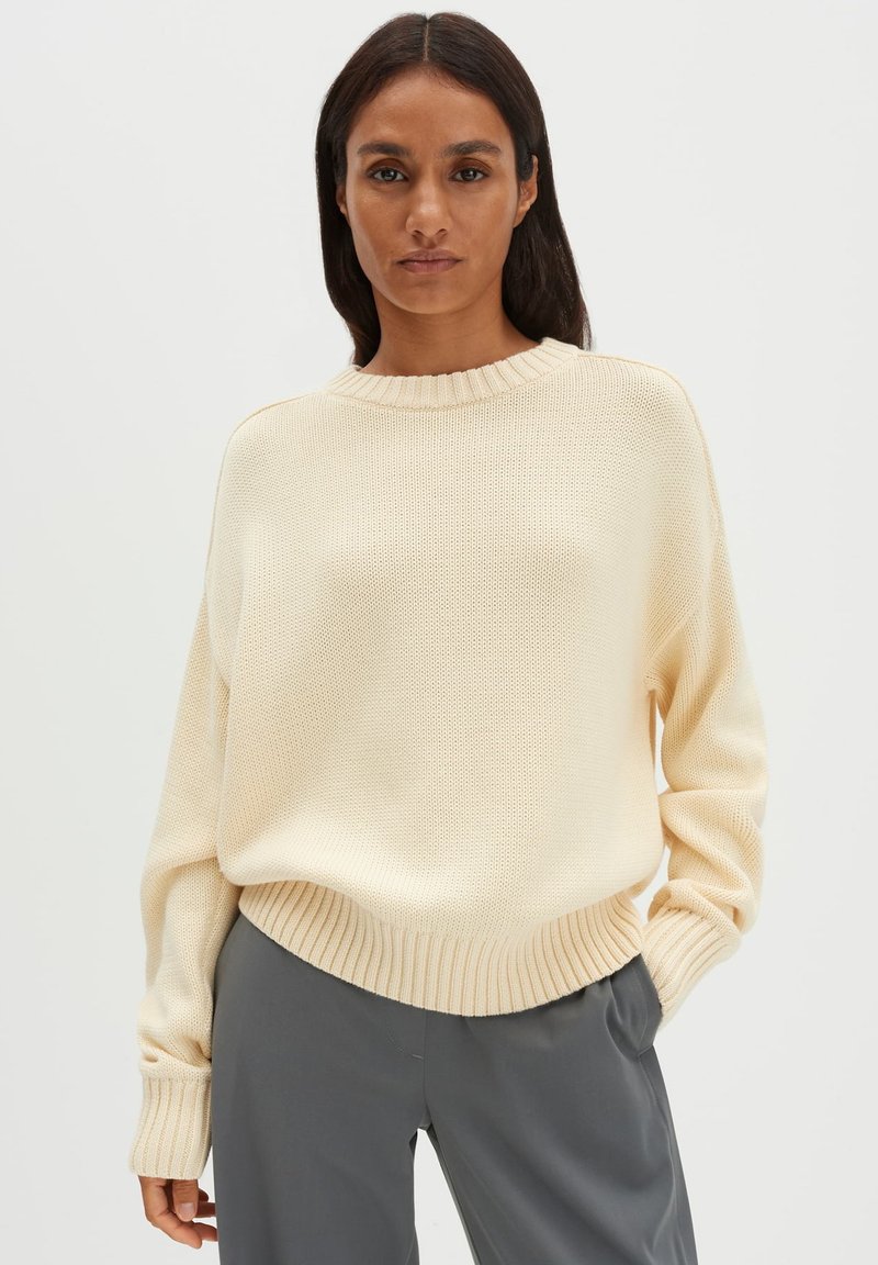 Maglione beige chiaro lavorato a maglia con scollo rotondo, orlo a coste e maniche lunghe. Il tessuto presenta un motivo strutturato.