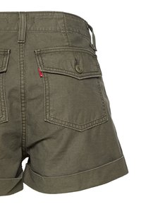Shorts taille haute vert olive avec poches à rabat au dos, fermetures à boutons, passants de ceinture et ourlets retroussés.