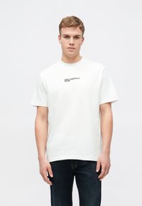 T-shirt branca de algodão com um logótipo impresso a preto "KARL LAGERFELD JEANS" no peito. Gola redonda, mangas curtas, corte descontraído.