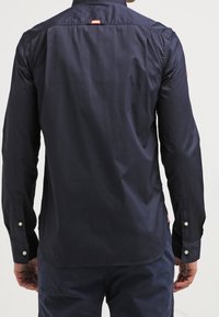 Námořnická košile s dlouhým rukávem z hladké bavlněné směsi, s manžetami na knoflíky, s klopeným límcem a malou nášivkou s logem na zadní straně.