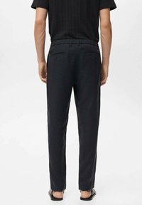 Pantalon noir léger avec une coupe décontractée ; doté d'une ceinture élastique, de deux poches arrière et d'une texture lisse. Design minimaliste.
