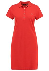 Vestido polo rojo de algodón, con cuello, manga corta y una botonera, con un pequeño logo en el lado izquierdo del pecho.