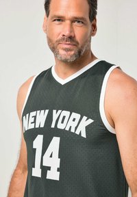 Camiseta de baloncesto verde con detalles blancos. Presenta "NEW YORK" impreso en letras blancas en negrita y el número "14" debajo. Material ligero de malla.