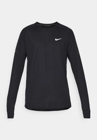 T-shirt de sport à manches longues noir, fabriqué en tissu texturé, avec un col rond, des manches raglan et un logo Nike blanc sur la poitrine.