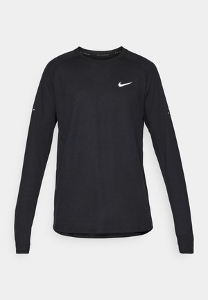 T-shirt de sport à manches longues noir, fabriqué en tissu texturé, avec un col rond, des manches raglan et un logo Nike blanc sur la poitrine.