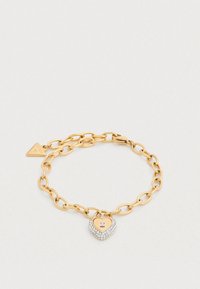 Βραχιόλι από χρυσή αλυσίδα με μενταγιόν σε σχήμα καρδιάς με ασημένια, λαμπερή επιφάνεια και λεπτομέρεια μηχανισμού κλειδώματος.