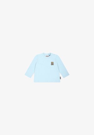 Maglietta azzurra chiaro a maniche lunghe per bambini con piccola grafica di orsetto sul petto sinistro e etichetta del marchio Moschino all’interno del colletto e nella cucitura laterale.