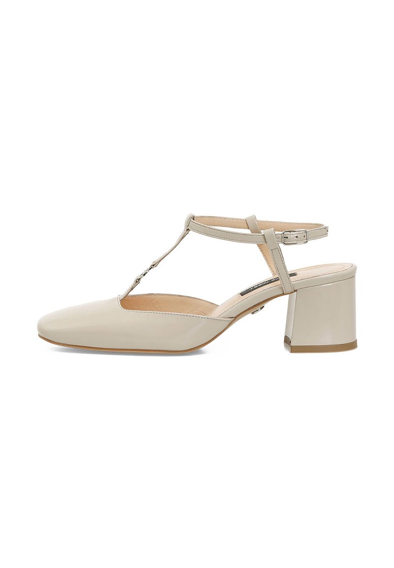 Chaussure slingback en cuir verni beige avec un bout carré et un talon bloc. Dotée d'une bride en T et d'une boucle réglable pour un maintien sécurisé.
