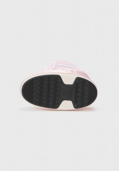 Zapatilla rosa con una suela de goma texturizada que presenta patrones de agarre circulares, cordones blancos y un material superior liso.