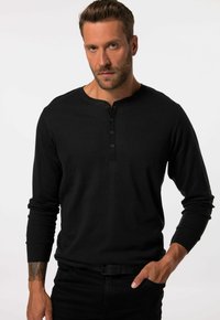 Musta pitkähihaisen henley-paita, jossa on ribbitekstuuri, py�öreä kaula-aukko ja kolme nappia rinnassa. Yhdistetty mustiin farkkuihin.