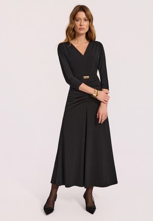 Czarna sukienka z głębokim dekoltem w kształcie V, długimi rękawami i marszczonym talią. Posiada centralny złoty akcent metalowy. Gładki materiał i długość do kostek.