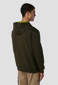 Felpa verde scuro con tasca a marsupio frontale, cappuccio regolabile con cordino e polsini a coste. Presenta una texture morbida e una vestibilità rilassata.