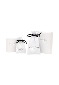 Des sachets en tissu blanc avec des cordons noirs, un petit et un plus grand, à côté d'une boîte blanche avec le texte noir "SATELLITE PARIS-FRANCE."