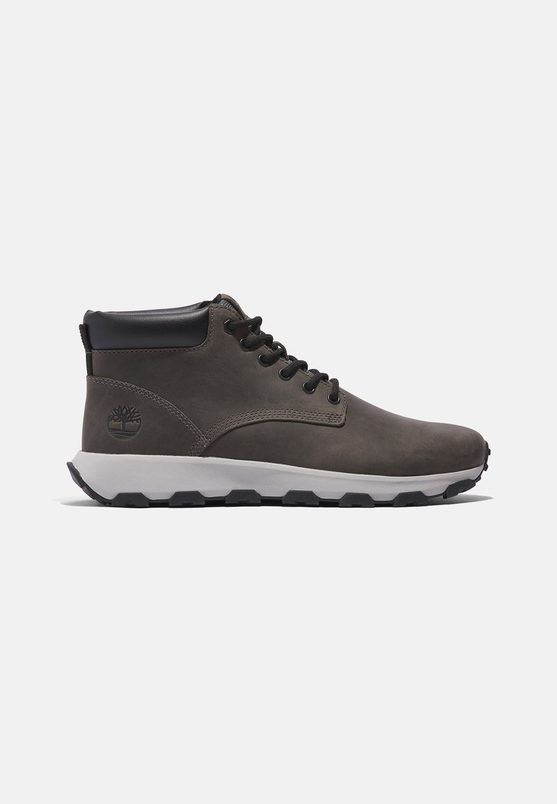 Botas de cuero marrón de altura media con textura suave, acentos negros, punta redonda y suela blanca con un patrón de agarre texturizado.