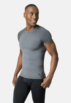 Grey athletic shirt with short sleeves and mesh texture on shoulders, paired with black cycling tights. Form-fitting design, smooth fabric.