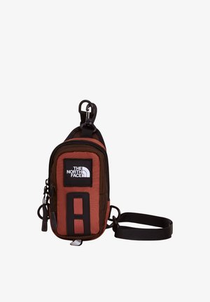 Mała brązowo-czarna saszetka North Face z zamkiem błyskawicznym, logo z przodu, klipsem i regulowanym paskiem do noszenia lub przypięcia.