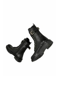 Černé kožené kotníkové boty s vysokým špičatým vrškem, se zipem na přední straně, šněrováním a bočním přezkovým uzávěrem. Tlustá gumová podrážka s texturou.
