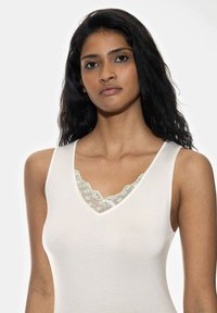 Light cream tank top featuring a V-neck design, lace trim with blue floral embroidery, and a smooth texture.