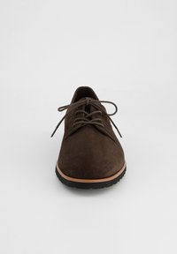 Chaussure en daim marron foncé à lacets avec bout arrondi, garniture beige et semelle en caoutchouc noir, vue de face sur fond blanc uni.