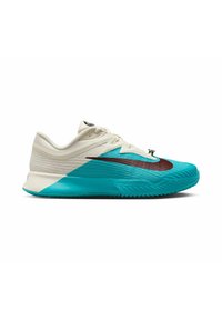 Zapatilla deportiva de Nike con una combinación de colores turquesa y crema, parte superior de malla, superficie texturizada y suela de goma con un diseño prominente.