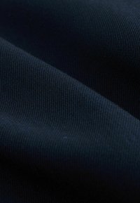 Marineblaue Stoff mit einer strukturierten, gerippten Oberfläche. Das Material wirkt dehnbar mit gewellten Falten und zeigt eine tiefe, gleichmäßige Farbe.