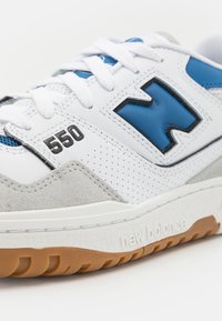 Baskets en cuir blanc avec des accents bleus, panneau en suède gris, design perforé, détails noirs 550 et semelle en caoutchouc gomme.