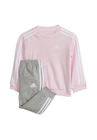 Felpa rosa con strisce bianche e logo sul petto, abbinata a pantaloni della tuta grigi con strisce bianche e logo sulla coscia.