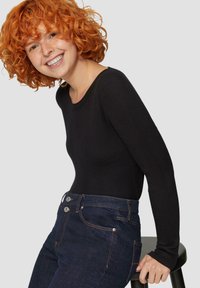 Zwarte geribbelde lange mouw top gecombineerd met donkerblauwe denim jeans met vijfknops sluiting en stikselaccenten. Eenvoudig, nauwsluitend ontwerp.