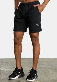 Black athletic shorts with an elastic waistband and side pockets, featuring a white RVA logo on the front. Worn with black sneakers.