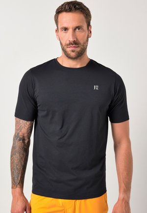 Czarny t-shirt z krótkim rękawem, wykonany z gładkiego materiału, z okrągłym dekoltem i małym białym logo na klatce piersiowej. Brak widocznych wzorów lub akcentów.
