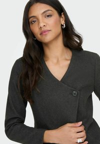 Tmavě šedá přiléhavá sako s výstřihem do V, dlouhými rukávy a jedním černým knoflíkem na zapínání. Hladký vlněný vzhled, přizpůsobený design.