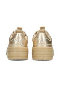 Sneaker metallizzati d'oro con suola spessa e trasparente; dettagli testurizzati sul retro; linguetta su ciascun tallone. Parte superiore liscia con design arrotondato.