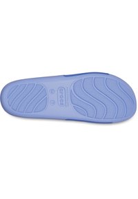 Semelle de chaussure Crocs bleu clair avec motifs antidérapants texturés et marquages de taille, présentée sur un fond blanc.