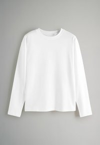 Maglietta bianca a maniche lunghe con scollo rotondo, vestibilità rilassata e texture liscia; nessun motivo o accento visibile. Orlo arrotondato nella parte inferiore.