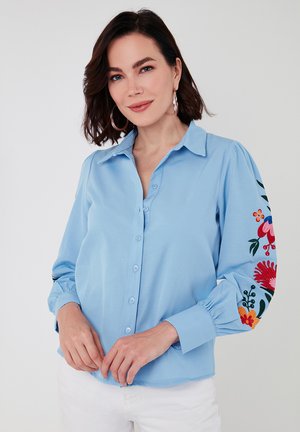 Light blue button-up shirt with balloon sleeves, featuring vibrant floral embroidery in red, orange, and green on the left sleeve.
